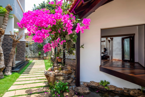 Hàng cây xanh mướt kết hợp cùng cây hoa giấy và tiểu cảnh hồ nước tạo nên phần độc đáo, ấn tượng cho ngôi nhà